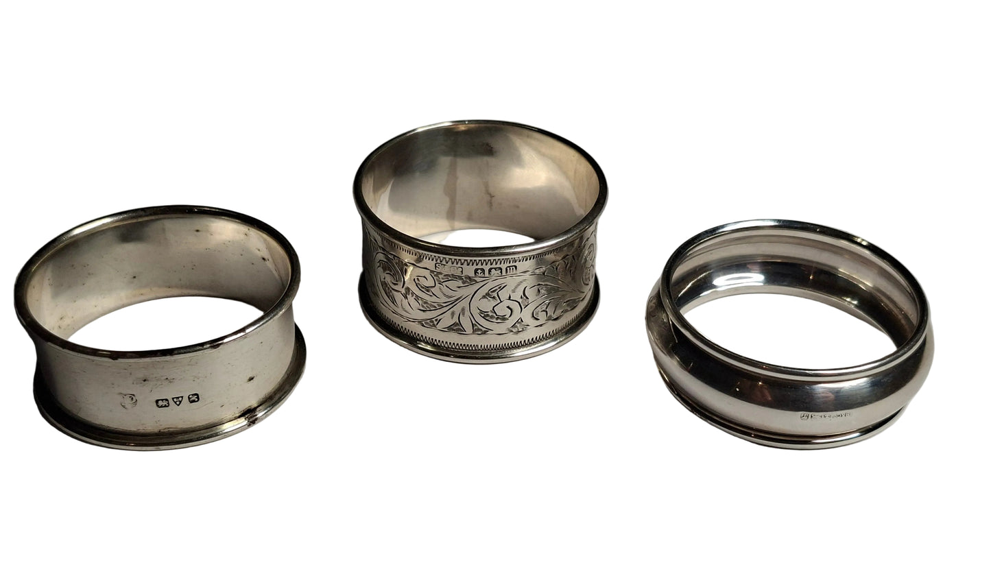 set of three antique solid silver napkin rings, including examples hallmarked Birmingham 1911 and Chester 1913, along with a third piece with rubbed hallmarks.