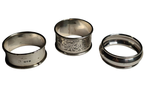 set of three antique solid silver napkin rings, including examples hallmarked Birmingham 1911 and Chester 1913, along with a third piece with rubbed hallmarks.
