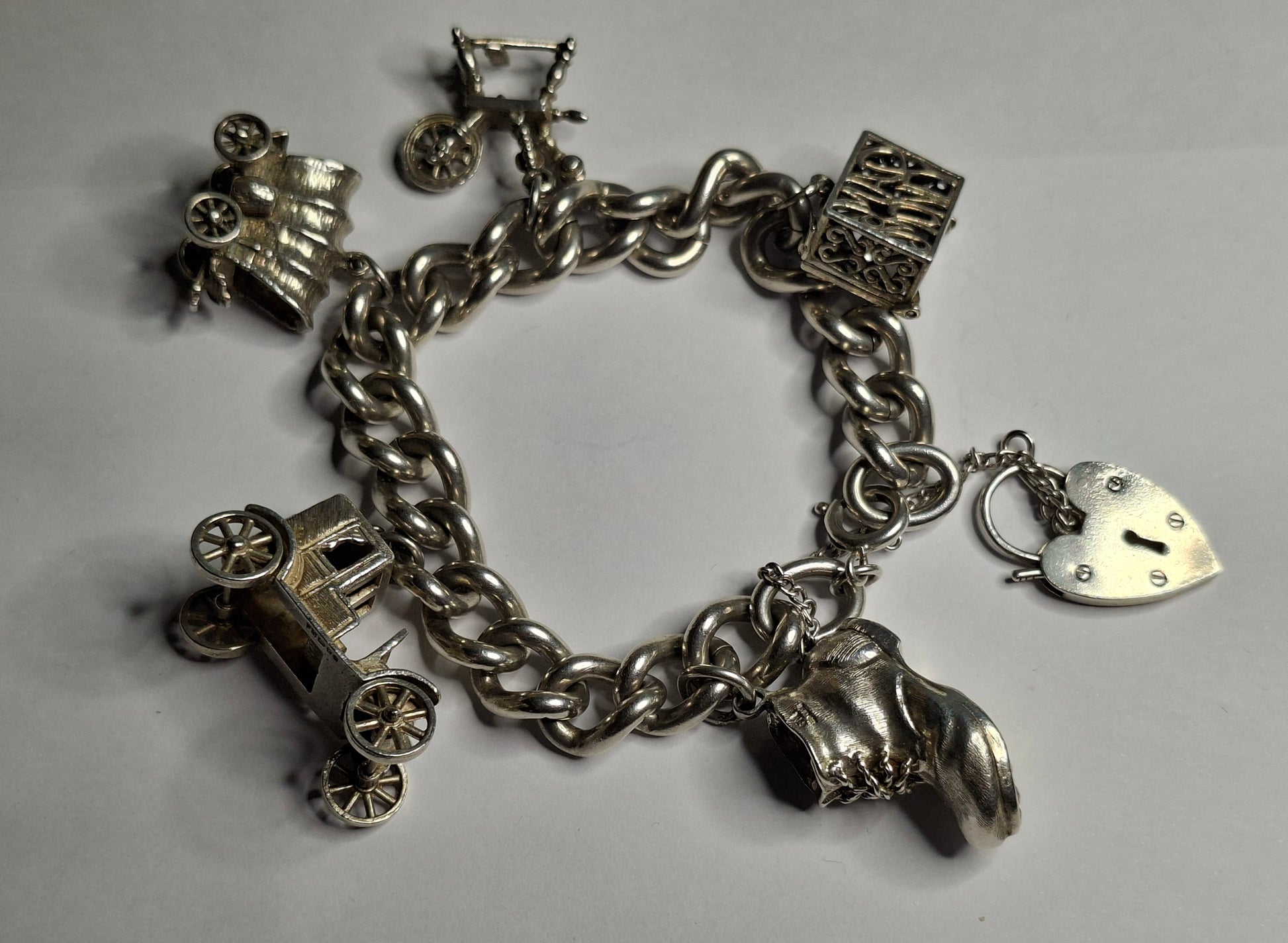 Silver charm bracelet with various charms on a gray background